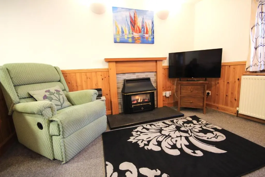 a living room with a fireplace and a tv at 23 Fairfield in Inverness