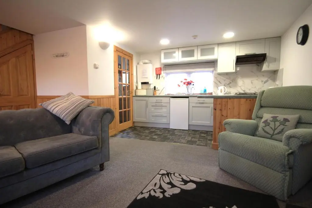 a living room with a couch and two chairs and a kitchen at 23 Fairfield in Inverness