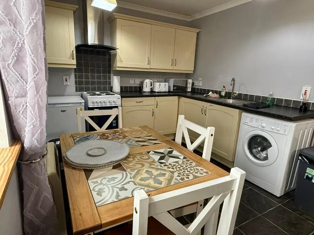a small kitchen with a table and a washer at The Old Salt House, Flat 2 in Wick