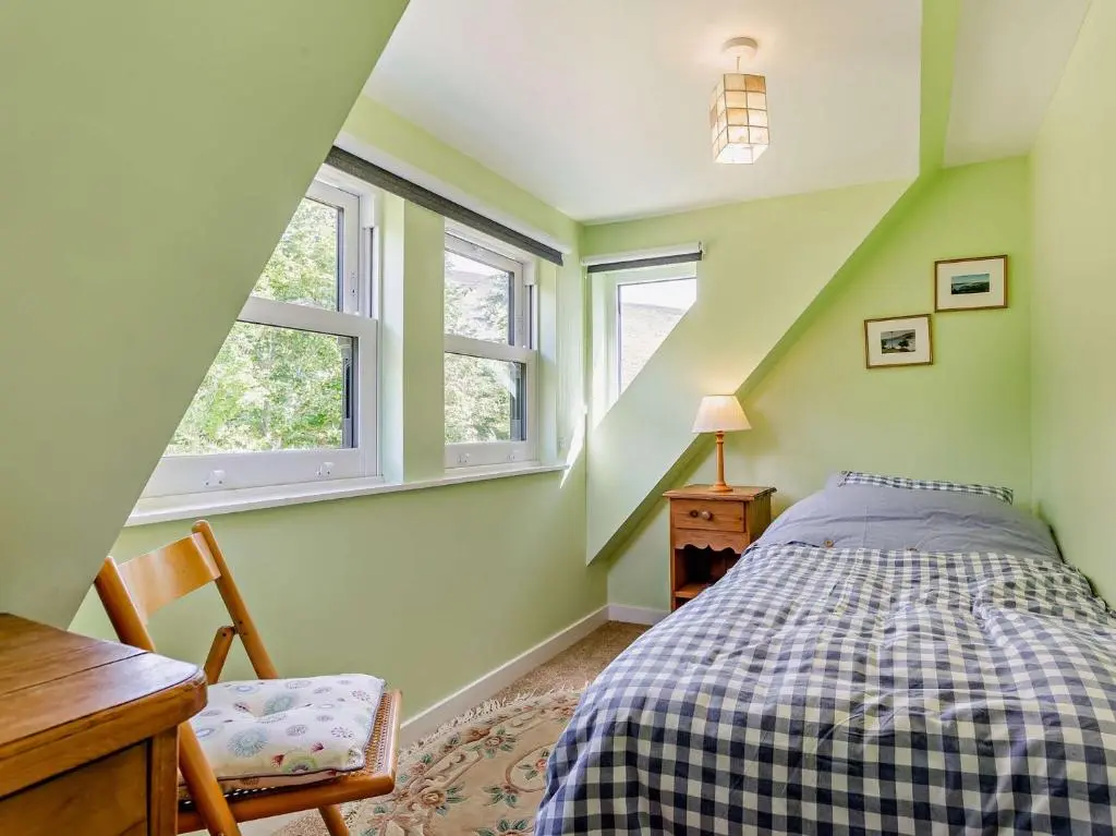a bedroom with a bed and a desk and two windows at 3 Bed in Kildonan SU192 in Helmsdale