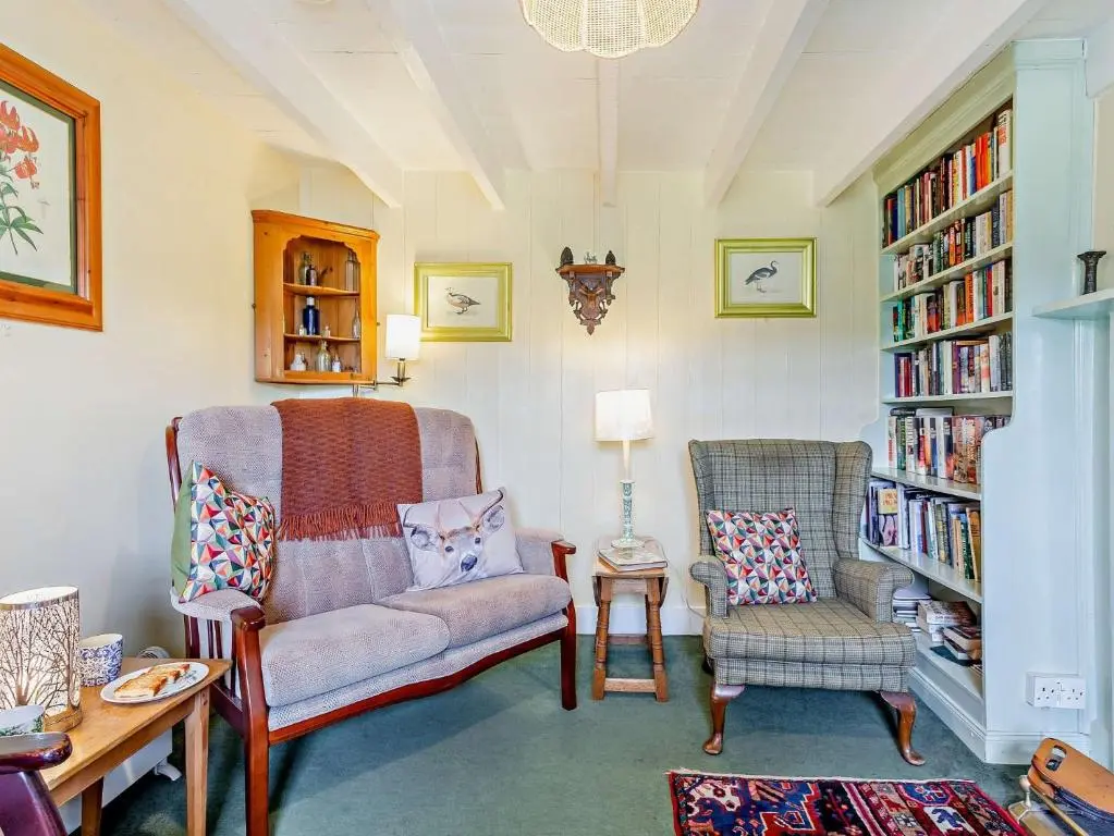 a living room with two chairs and a book shelf at 3 Bed in Kildonan SU192 in Helmsdale