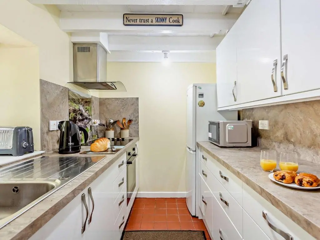 a kitchen with white cabinets and a sink at 3 Bed in Kildonan SU192 in Helmsdale