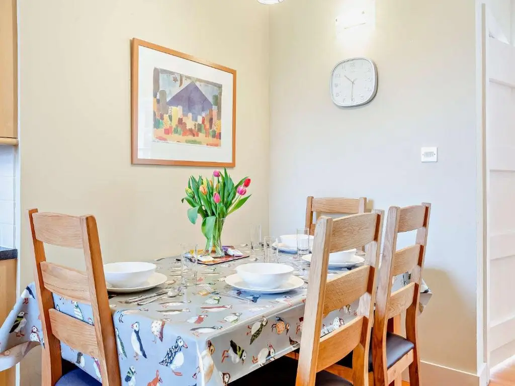 a dining room table with chairs and a vase of flowers at 2 Bed in Conon Bridge CA387 in Cononbridge