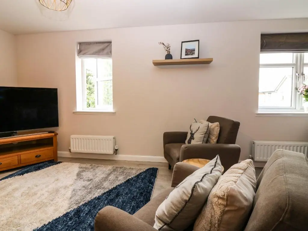 a living room with a couch and a flat screen tv at 11 Ambleside Court in Banchory