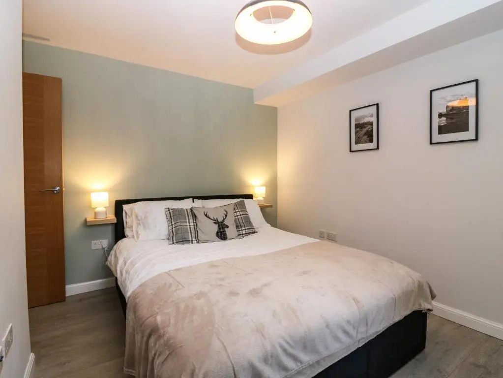 a bedroom with a large bed with two lamps at 11 Ambleside Court in Banchory