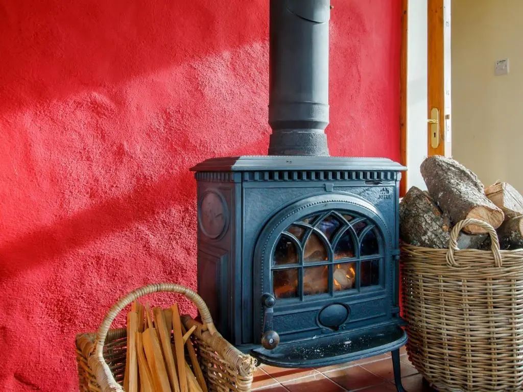 a blue stove next to a red wall with a basket at 3 Bed in Dinnet 53150 in Dinnet