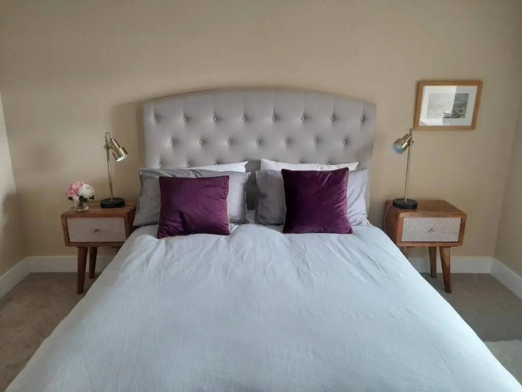 a bedroom with a large bed with purple pillows at 3 Bed in Dinnet 53150 in Dinnet