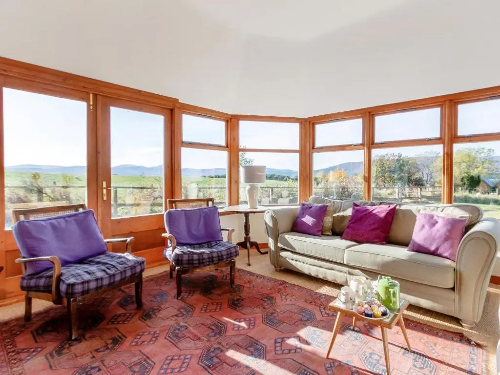 a living room with a couch and chairs and windows at 3 Bed in Dinnet 53150 in Dinnet