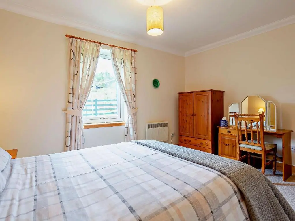 a bedroom with a bed and a dresser and a window at 1 Bed in Beauly 82779 in Beauly