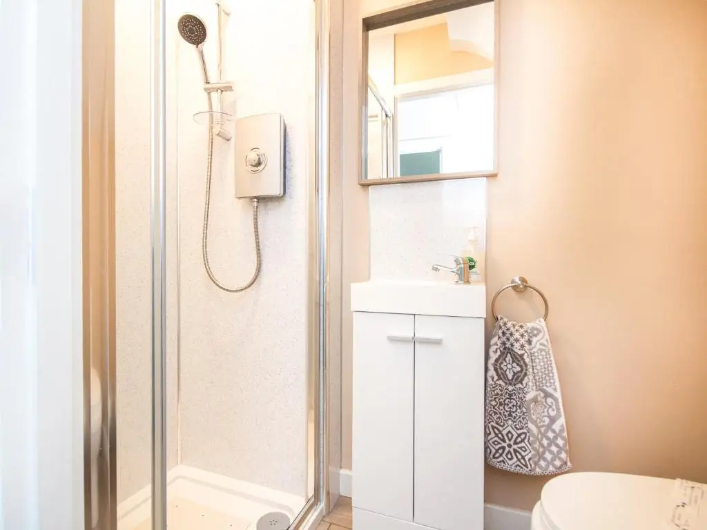 a bathroom with a shower and a toilet and a sink at Colbheinn Cottage in Brora
