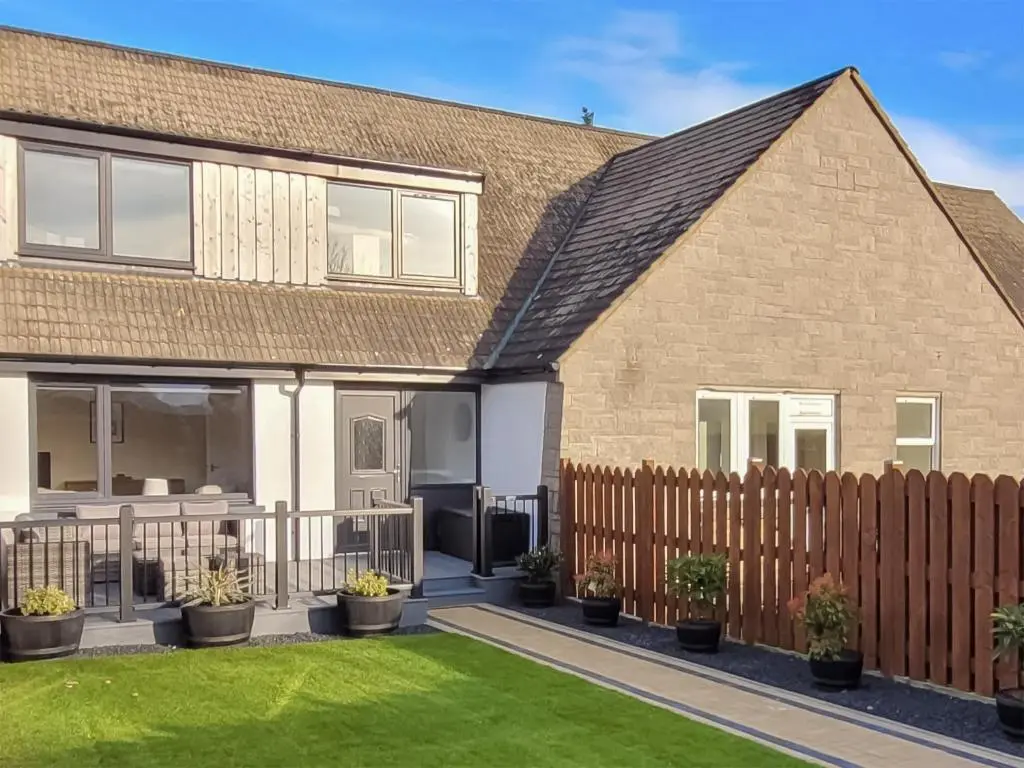 a house with a fence and a yard at Colbheinn Cottage in Brora