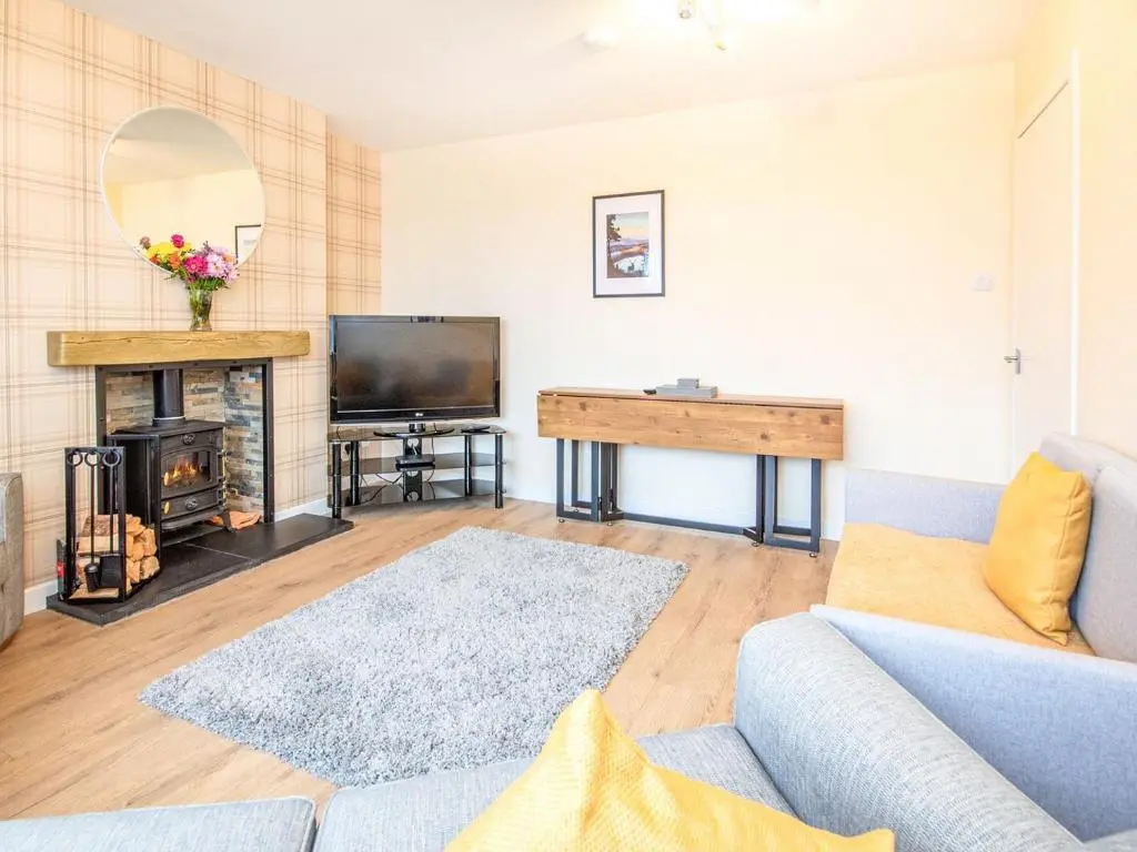 a living room with a couch and a television at Colbheinn Cottage in Brora