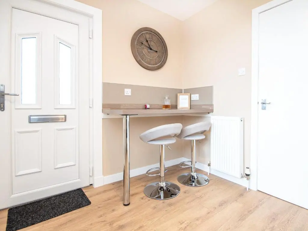 a room with two stools and a clock on the wall at Colbheinn Cottage in Brora
