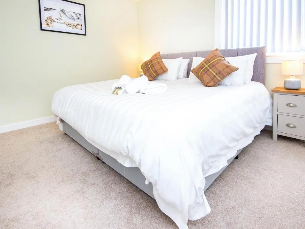 a bedroom with a large white bed with two stuffed animals on it at Colbheinn Cottage in Brora