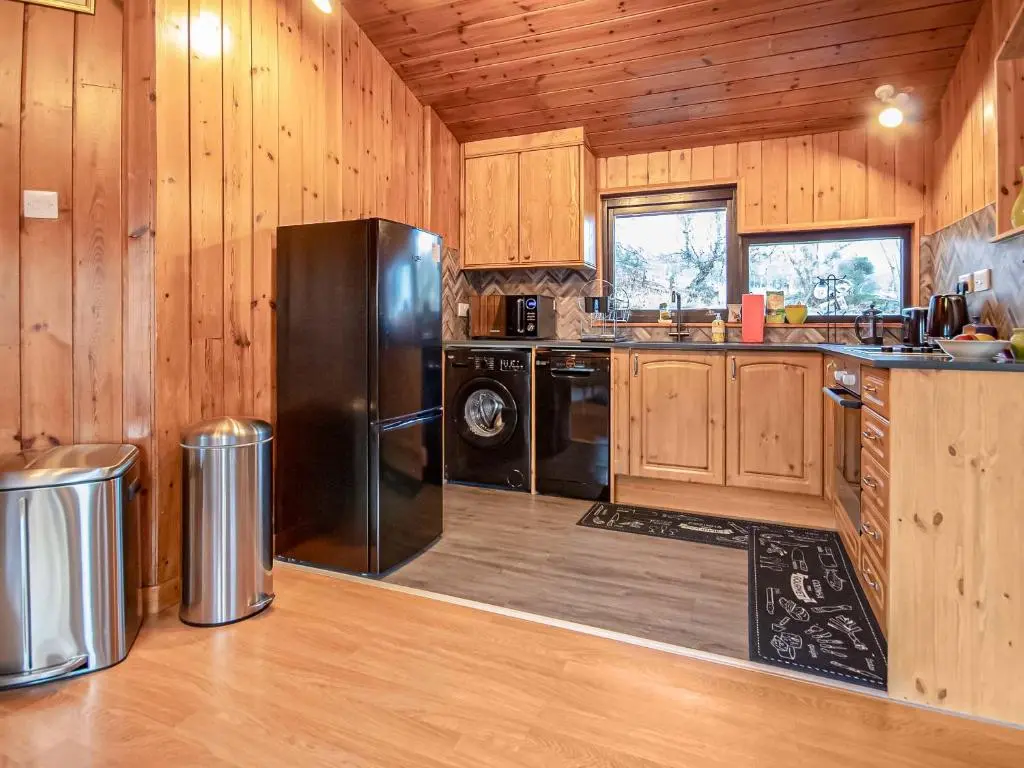 a kitchen with wooden walls and a black refrigerator at Dornie Lodge in Beauly