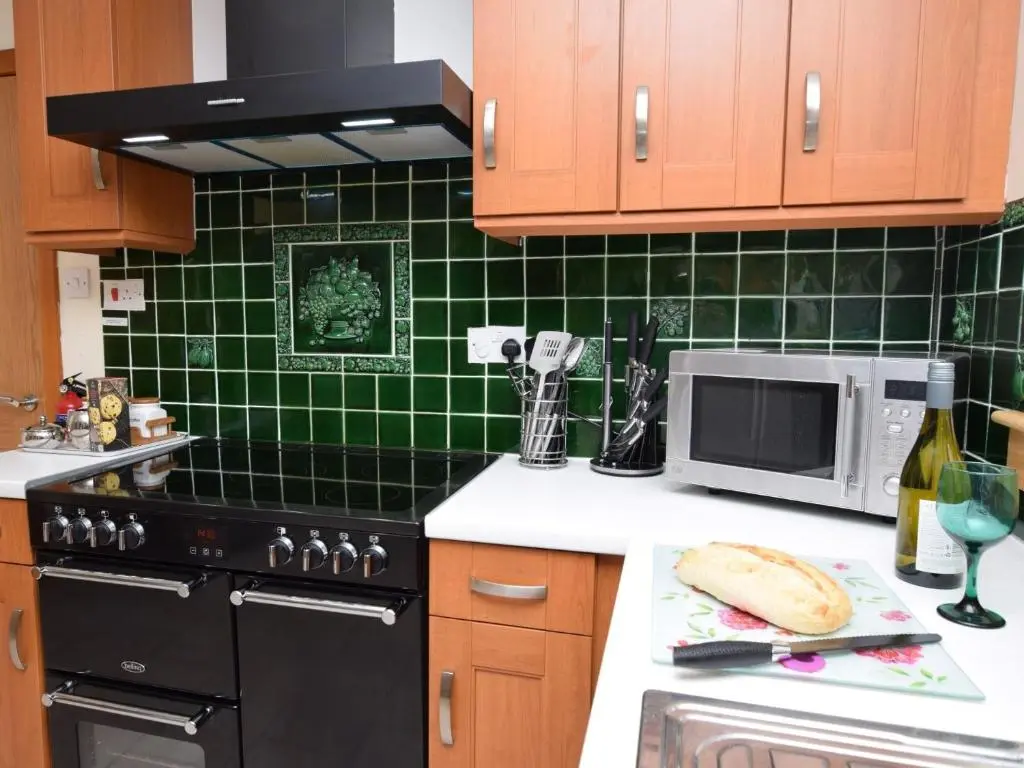 a kitchen with a black stove and a microwave at 3 Bed in Drumnadrochit IN633 in Balnain