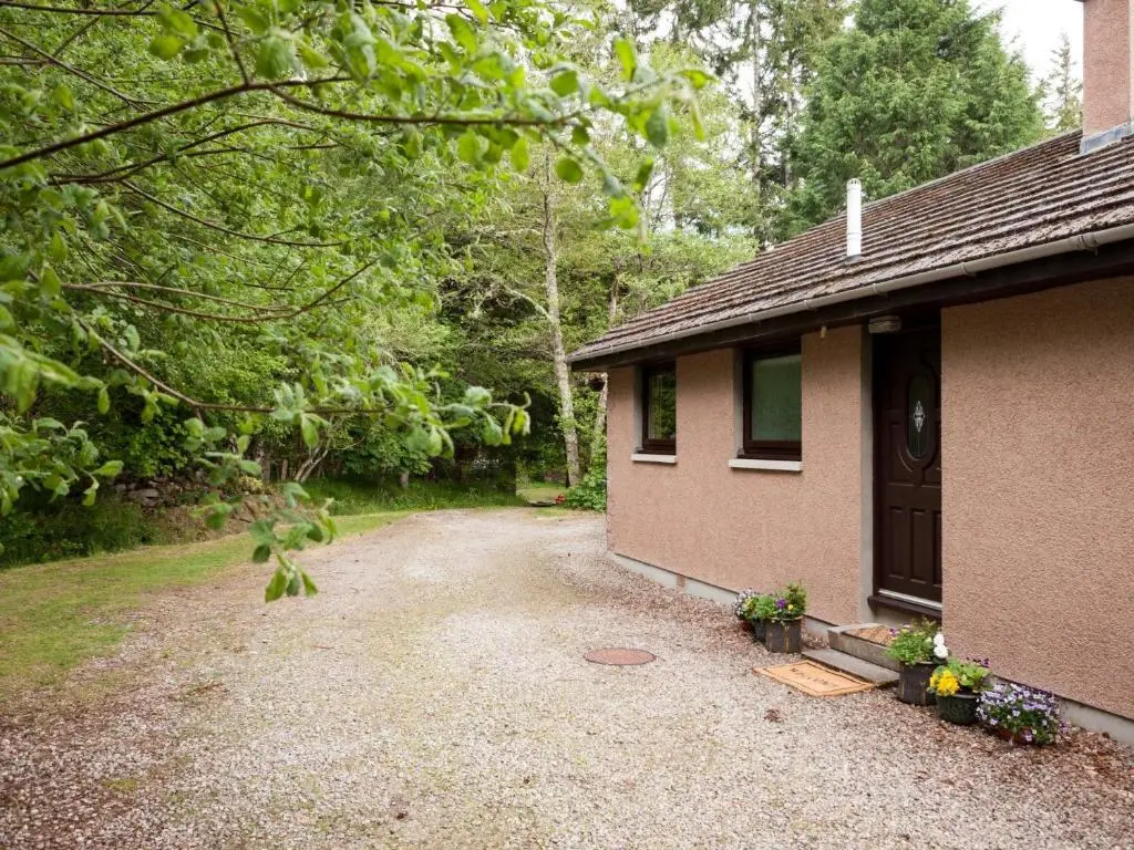 a house with a gravel driveway next to a building at 3 Bed in Drumnadrochit IN633 in Balnain