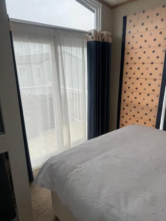 a bedroom with a bed and a large window at Aurora luxury beach lodge in Lossiemouth