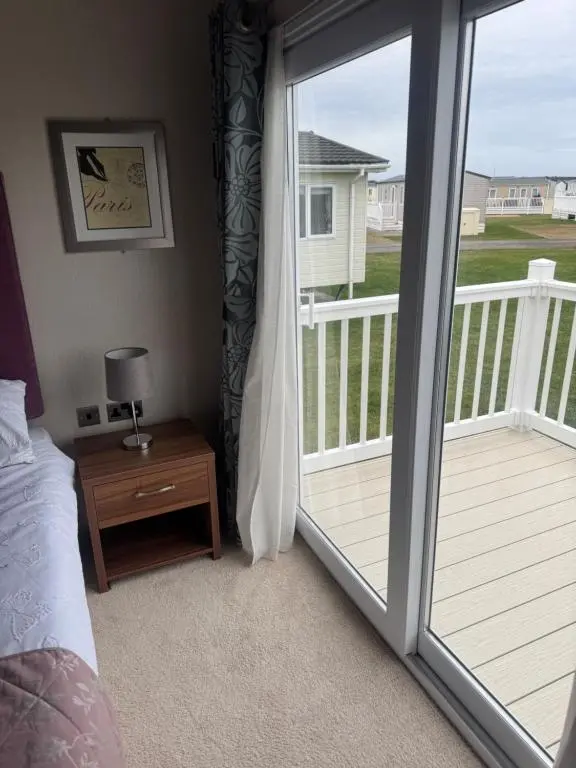 a bedroom with a door open to a balcony at Aurora luxury beach lodge in Lossiemouth