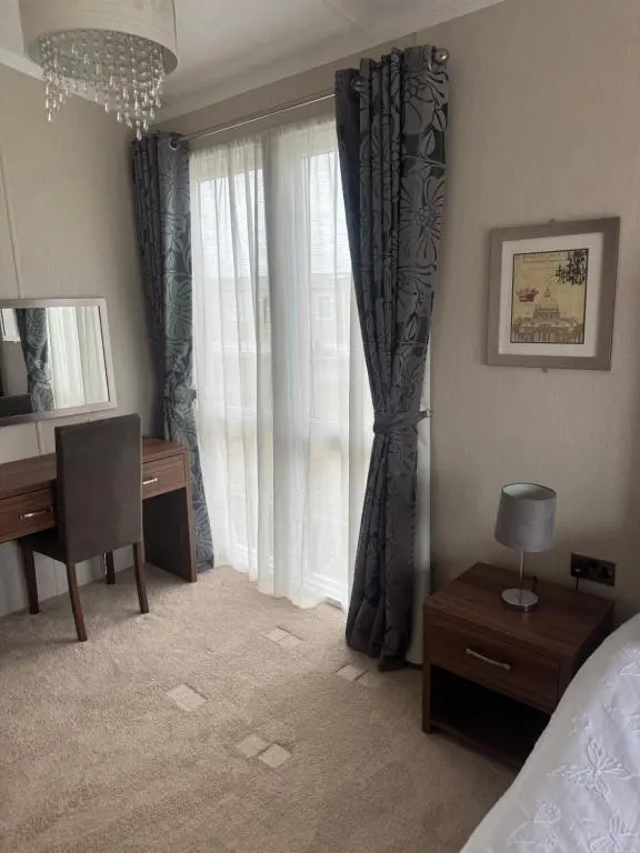a bedroom with a bed and a desk and a window at Aurora luxury beach lodge in Lossiemouth