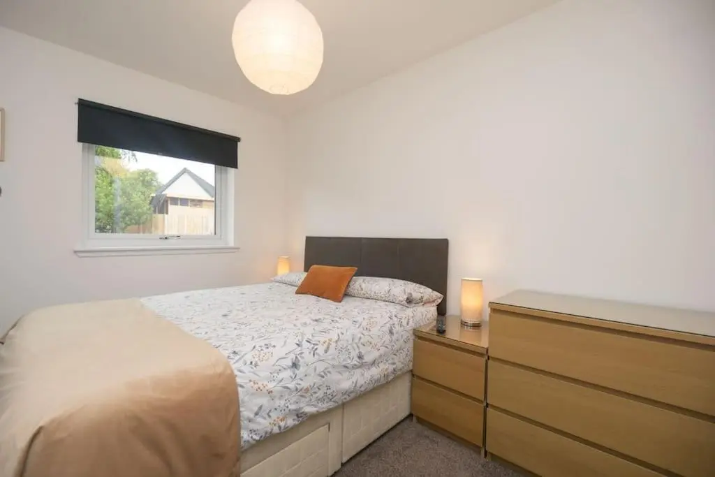 a bedroom with a bed and a dresser and a window at Elgin, home from home in Elgin