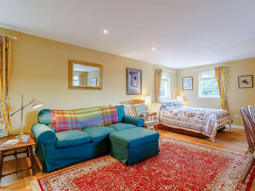 a living room with a blue couch and a bed at 1 Bed in Balblair 89058 in Culrain
