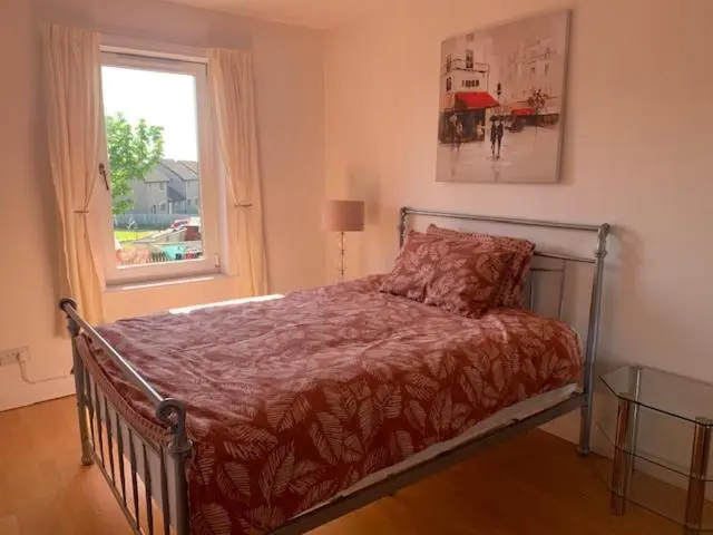 a bed in a bedroom with a window and a bedspread at Modern One Bedroom Apartment in Lossiemouth