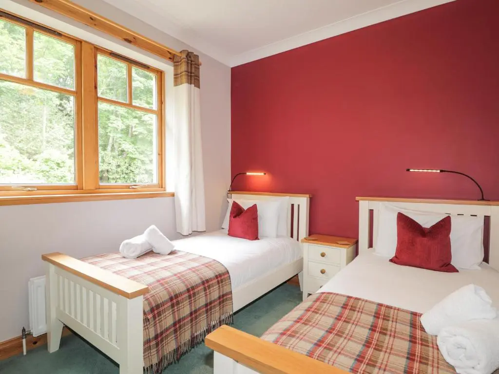 two beds in a room with red walls at Rossie Lodge in Inverness