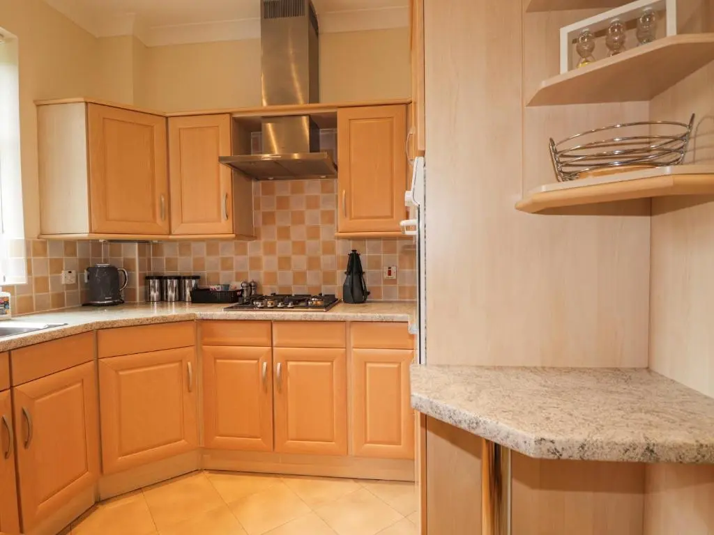 a kitchen with wooden cabinets and granite counter tops at Rossie Lodge in Inverness