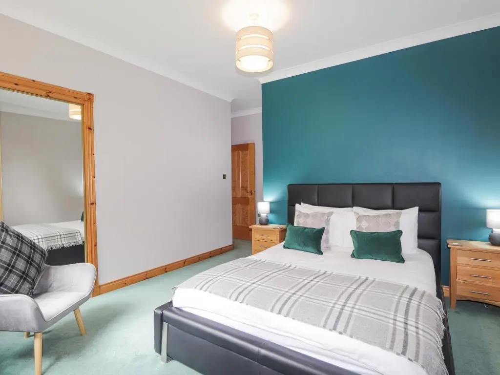a bedroom with a large bed and a chair at Rossie Lodge in Inverness