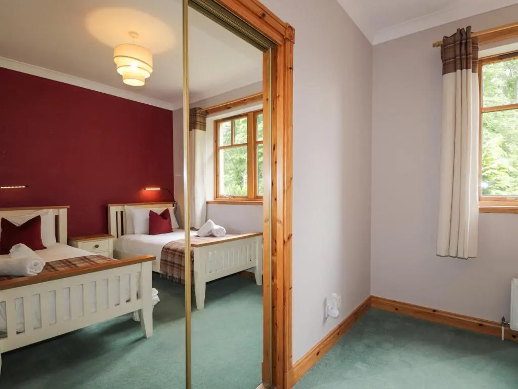a bedroom with two beds and a mirror at Rossie Lodge in Inverness