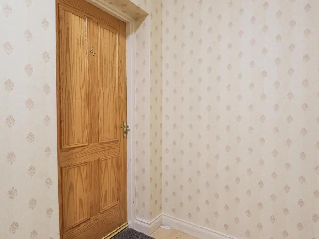an empty room with a wooden door and wallpaper at Rossie Lodge in Inverness