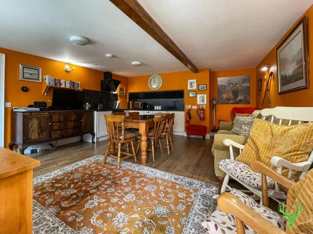 a living room with orange walls and a table and chairs at The Secret Garden at Old Drynie House - Self Catering in Inverness