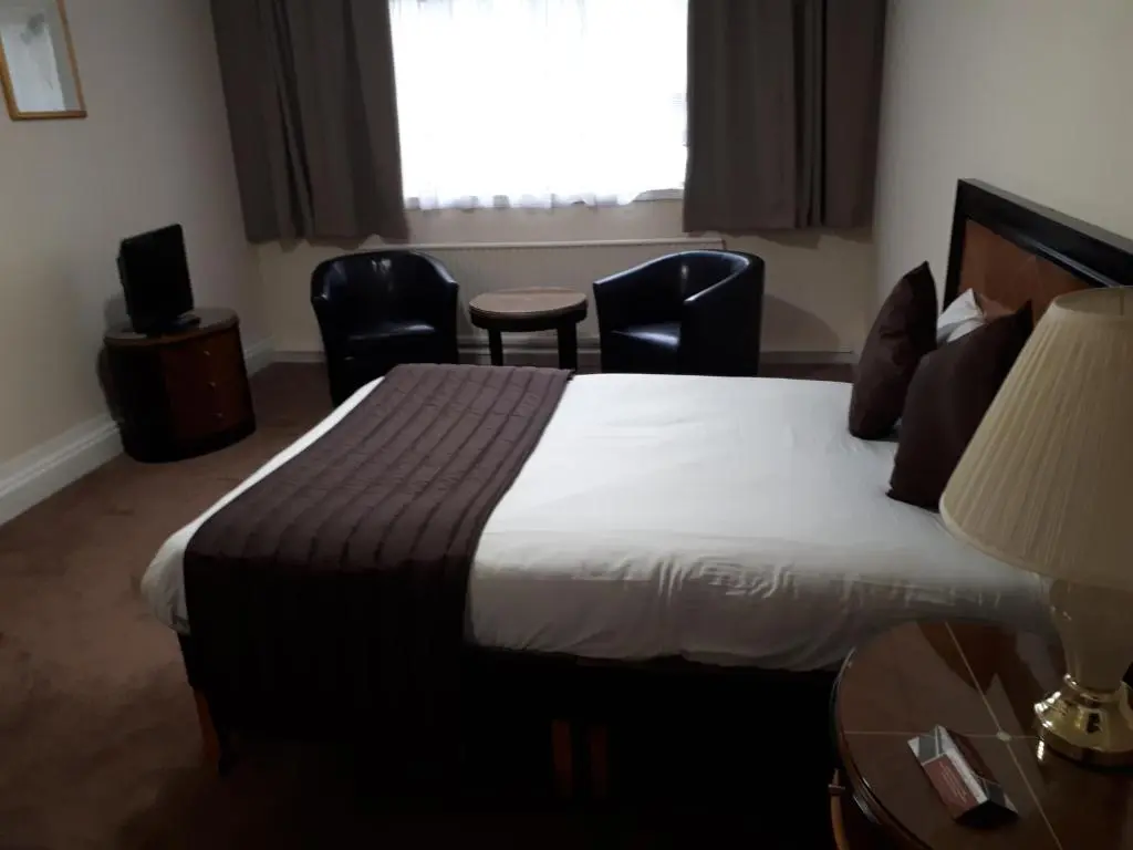 a hotel room with a bed and chairs and a window at Britannia Hotel Aberdeen in Aberdeen