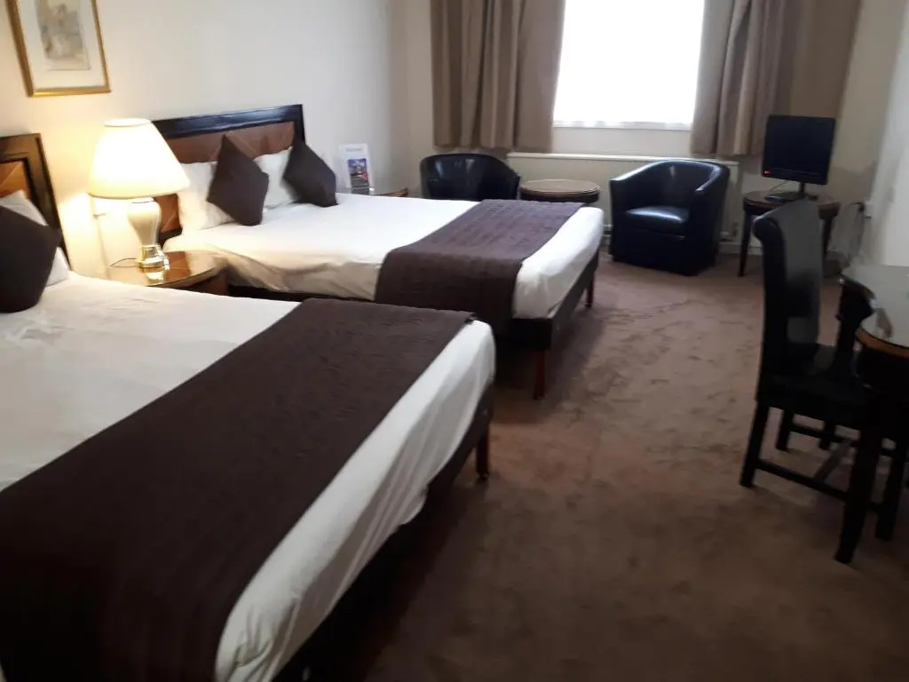 a hotel room with two beds and chairs and a window at Britannia Hotel Aberdeen in Aberdeen