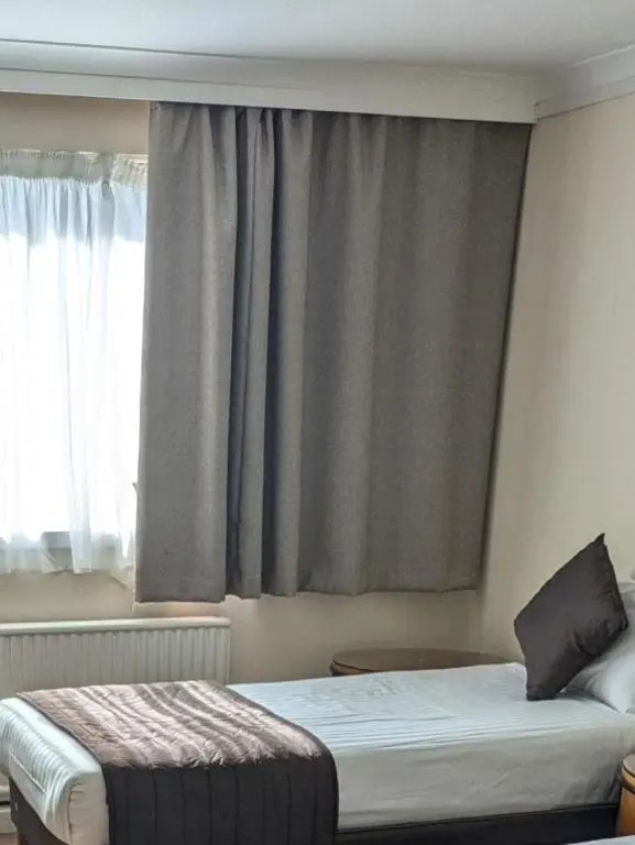 a bedroom with two beds in front of a window at Britannia Hotel Aberdeen in Aberdeen