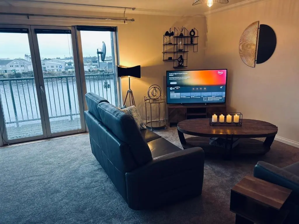 a living room with a couch and a table and a television at Central Cosy Riverview Apartment 2 bed, 2 bath, Free Parking / WiFi in Inverness