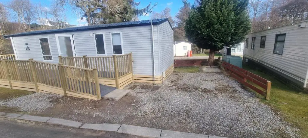 a home with a wooden fence next to a house at Lynton lodges ATLAS in Evanton