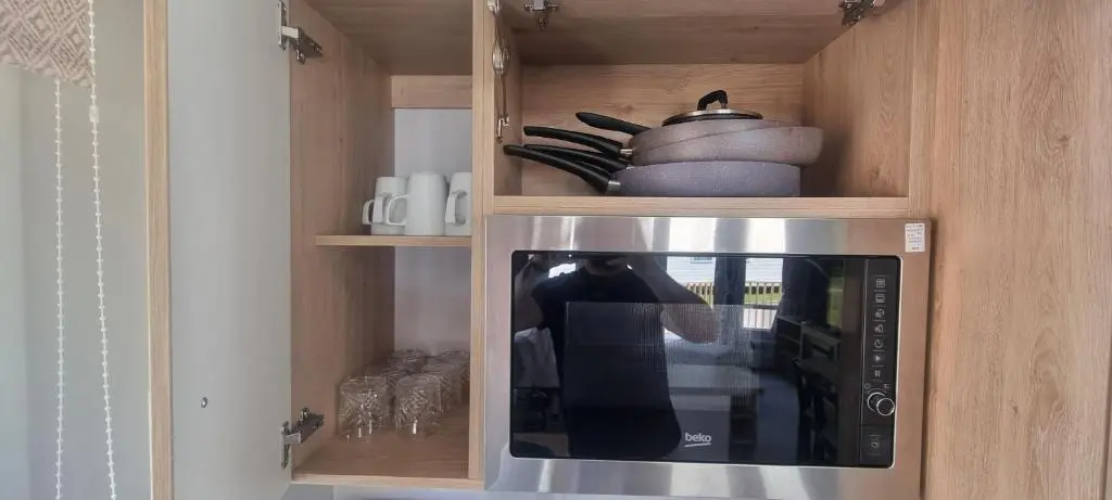 a kitchen with a microwave in a wooden cabinet at Lynton lodges ATLAS in Evanton
