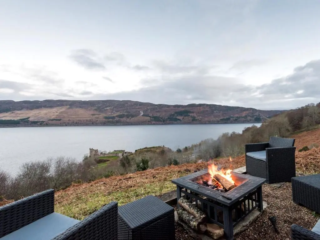 a fire pit with a view of a lake at 2 bed in Loch Ness CA315 in Drumnadrochit