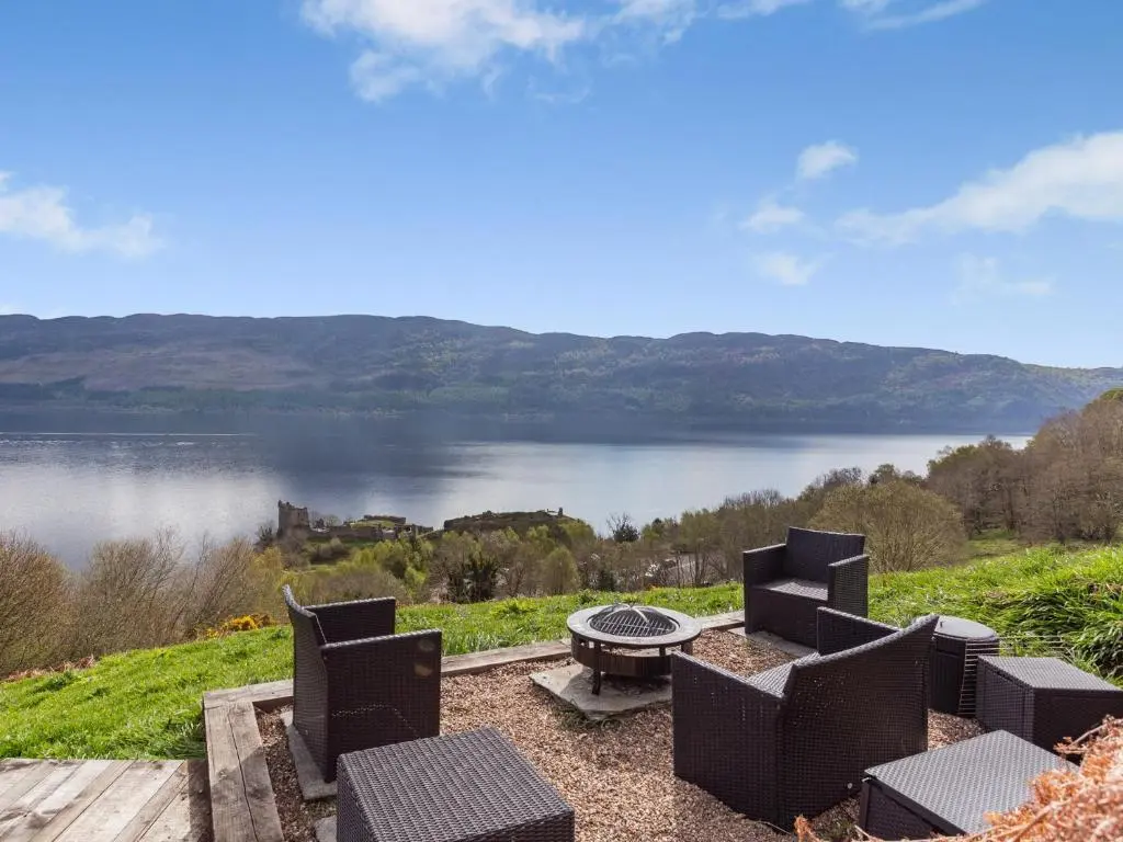 a view of a lake with chairs and a table at 2 bed in Loch Ness CA315 in Drumnadrochit