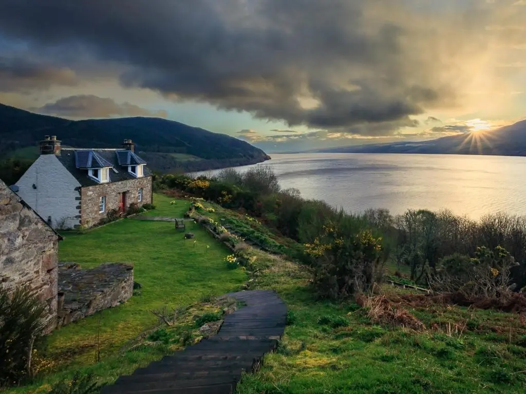 a house on a hill next to a body of water at 2 bed in Loch Ness CA315 in Drumnadrochit