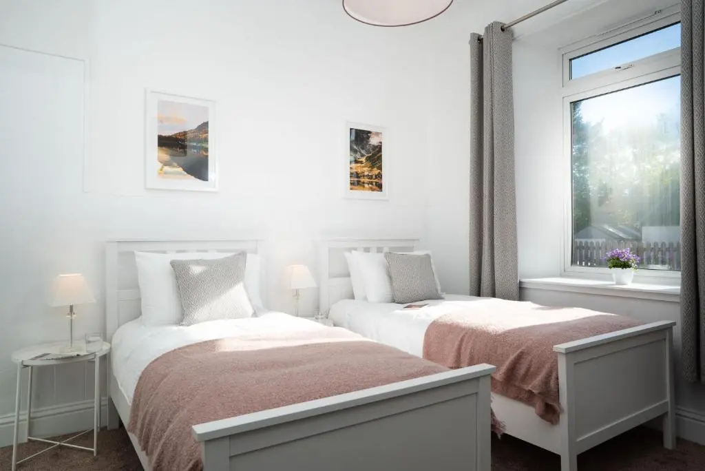 a white bedroom with two beds and a window at Nethy Station - Seasgair Lodges in Nethy Bridge