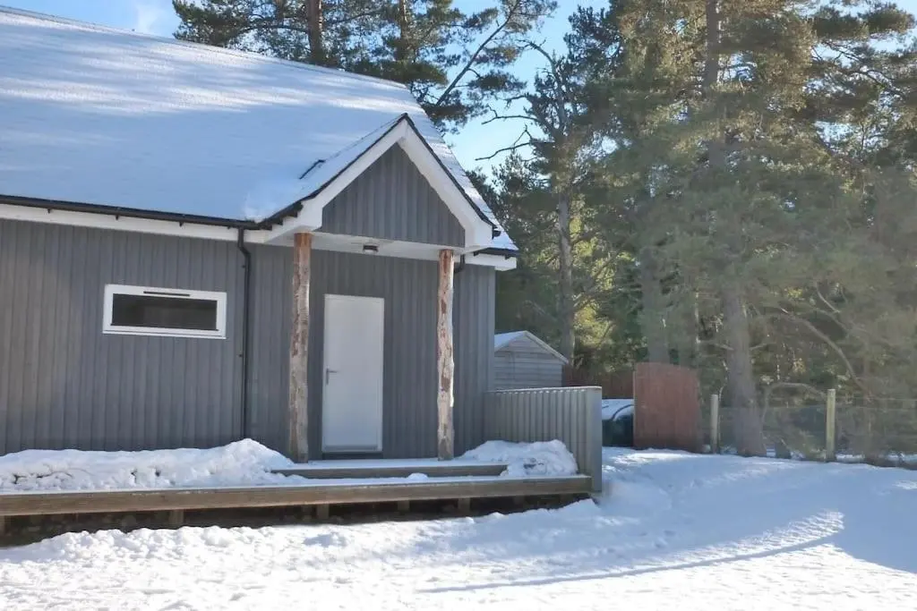 a small gray building with snow on the ground at The Bothy, Nethy Bridge in Nethy Bridge