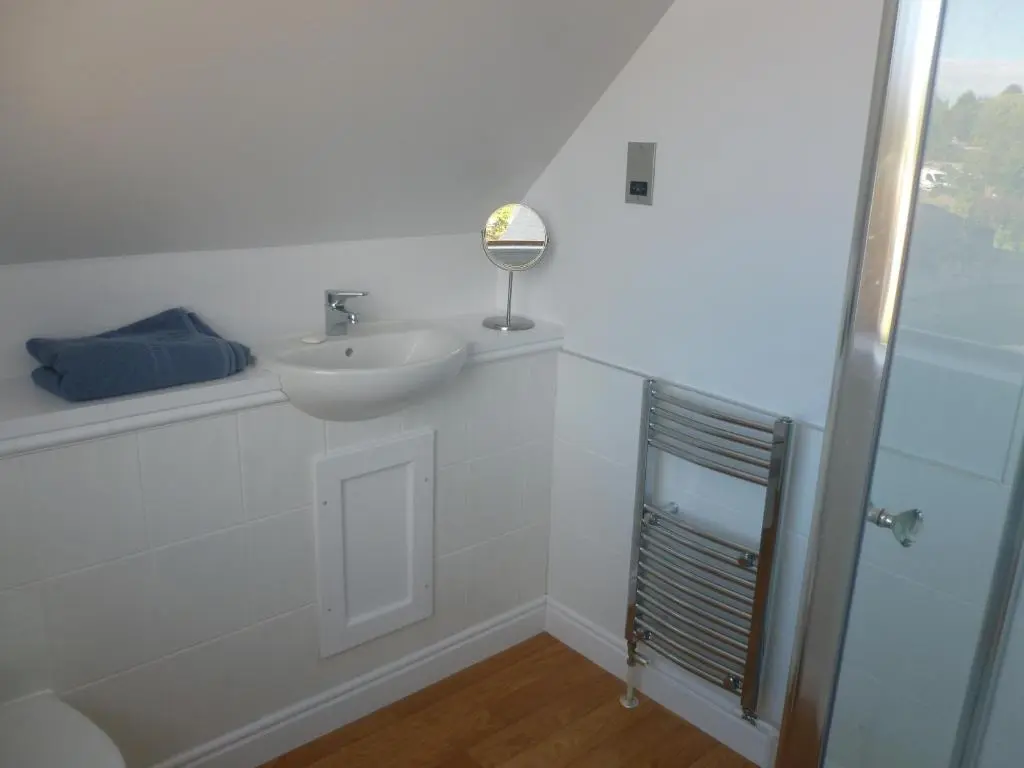 a white bathroom with a sink and a mirror at The Bothy, Nethy Bridge in Nethy Bridge