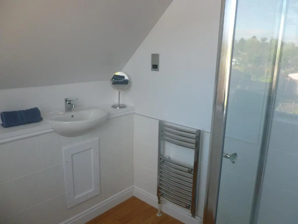 a white bathroom with a sink and a shower at The Bothy, Nethy Bridge in Nethy Bridge