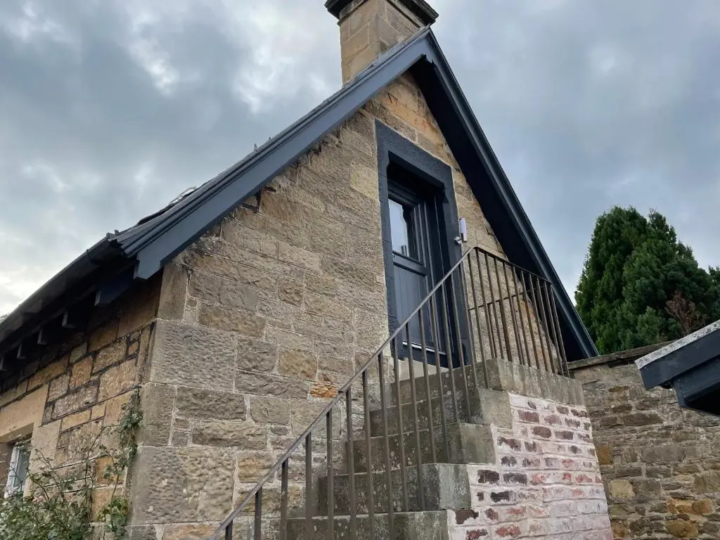 a window on the side of a stone building with a metal railing at Braemorriston Lodge in Elgin