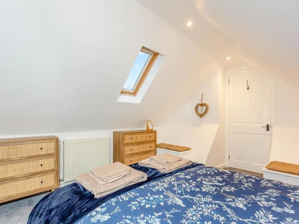 a bedroom with a bed and a dresser and a window at East Tarrel Cottage in Portmahomack