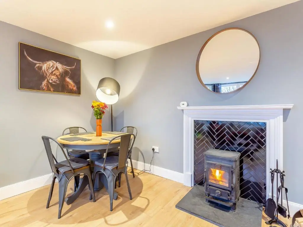 a dining room with a table and a fireplace at East Tarrel Cottage in Portmahomack
