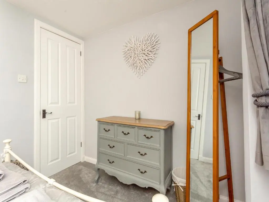a bedroom with a dresser and a mirror at East Tarrel Cottage in Portmahomack